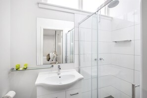 A modern bathroom with a glass shower enclosure, a white sink, and a mirror. - Nightcap at Hume Hotel (Yagoona)