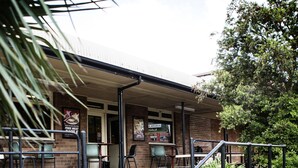 A building with a covered outdoor seating area, steps leading to the entrance, and a sign advertising free meat. - Nightcap at Hume Hotel (Yagoona)