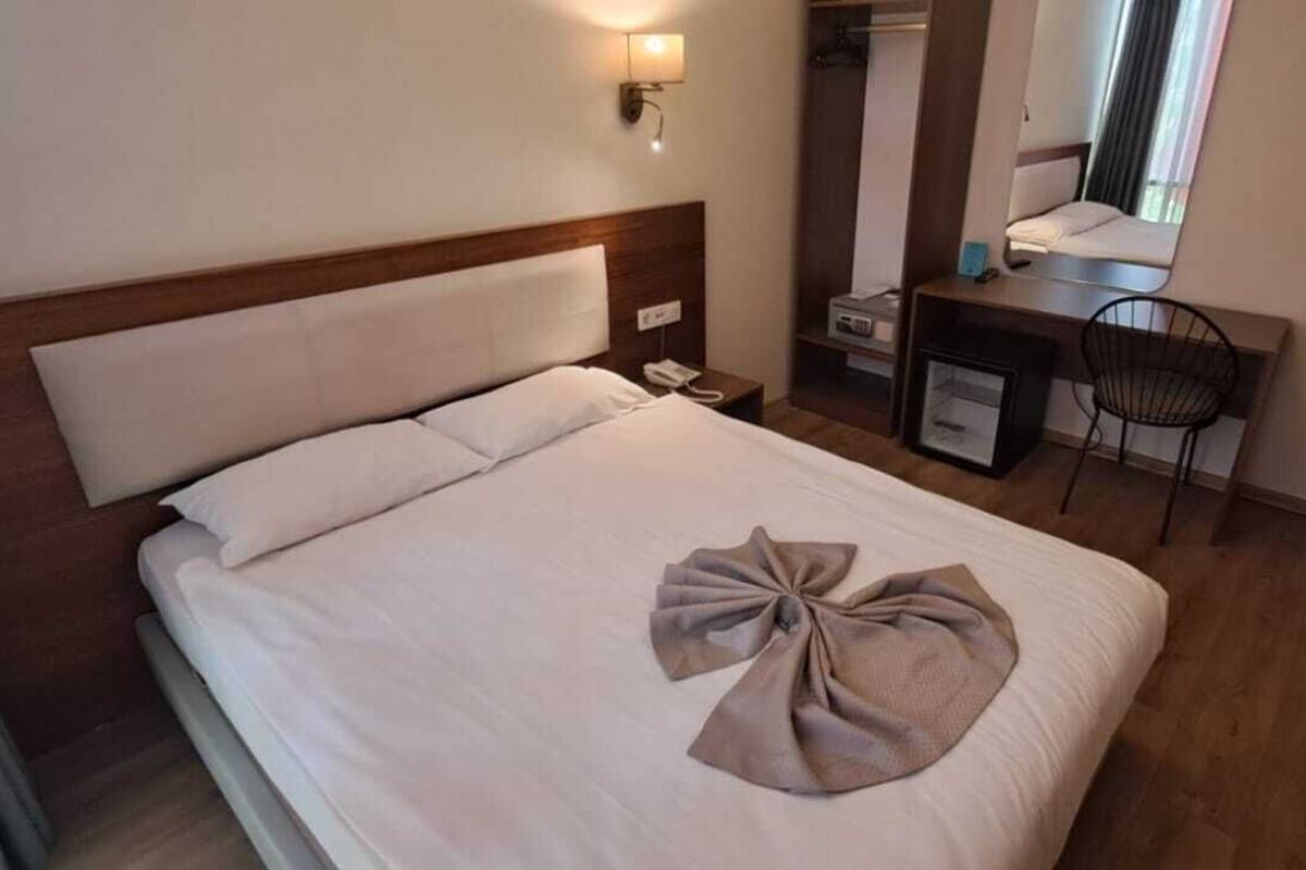 Ein Hotelzimmer mit Bett, Schreibtisch, Stuhl, Spiegel und Fernseher.