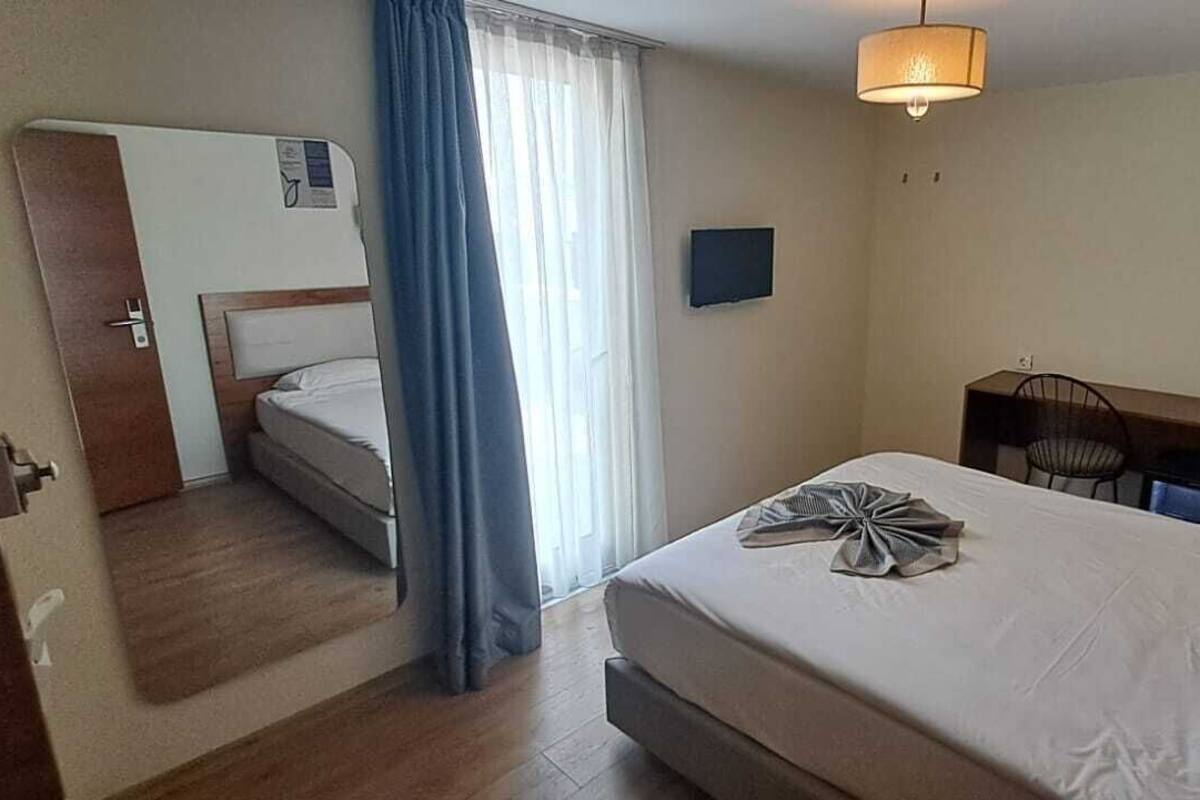 Ein Hotelzimmer mit Bett, Schreibtisch, Stuhl, Fernseher und Kleiderschrank.
