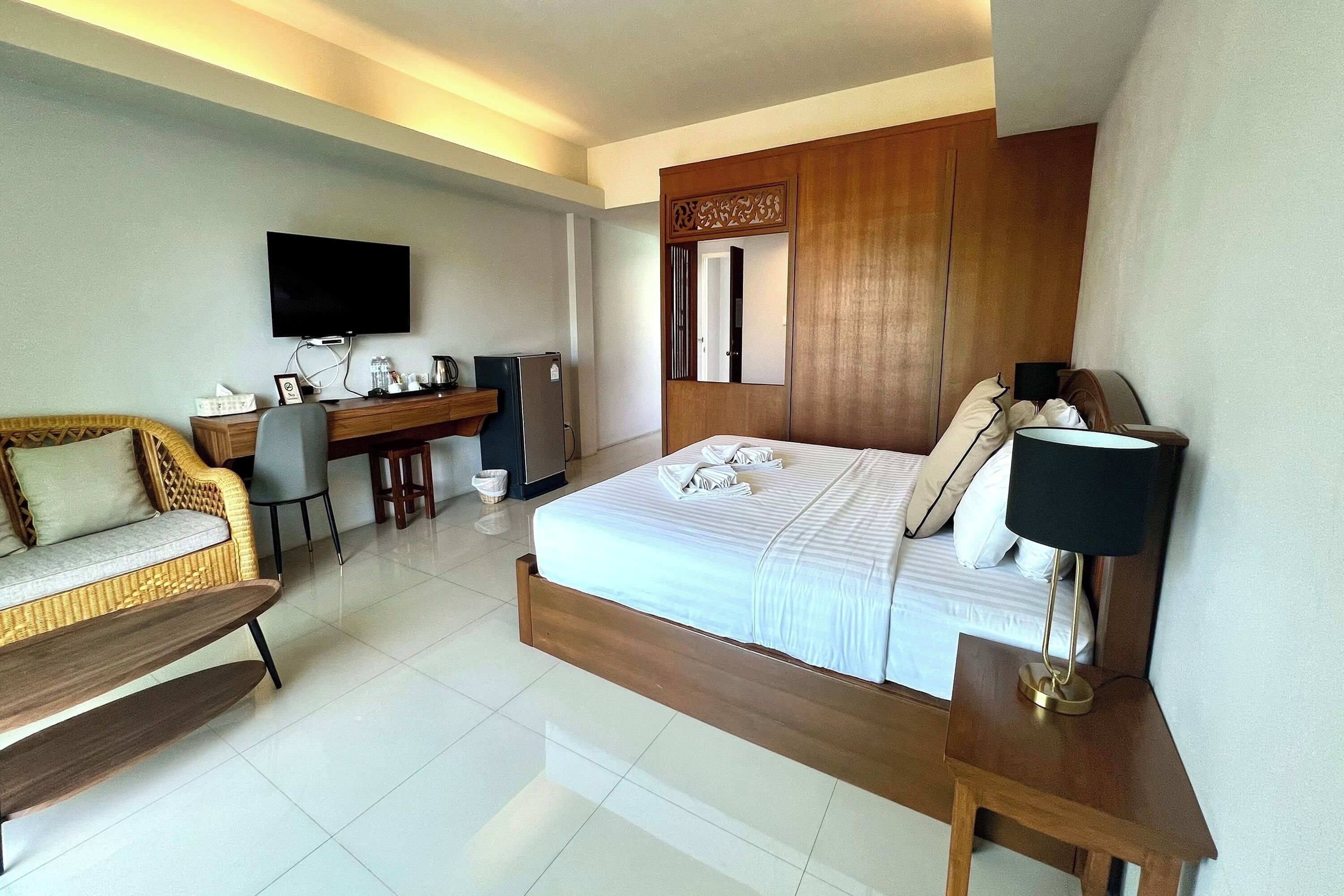 Habitación de hotel con cama, escritorio, televisión y zona de estar.