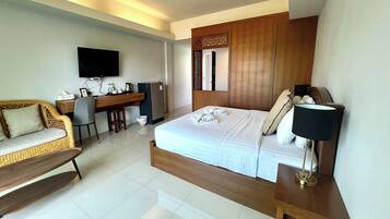 Habitación de hotel con cama, escritorio, televisión y zona de estar.