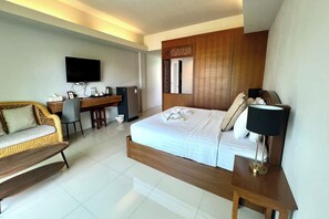 A hotel room with a bed, a desk, a television, and a seating area. - Phu Hun Sa Boutique Hotel (Nan)