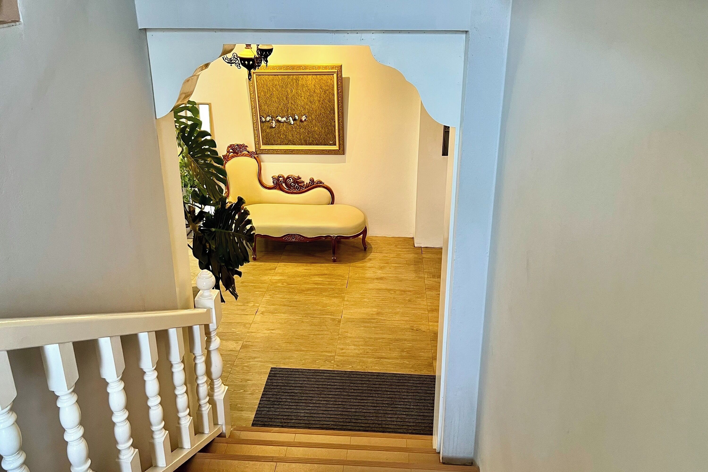 A staircase leading to a room with a yellow sofa and a framed artwork on the wall.