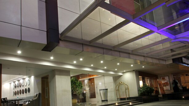 A hotel entrance with a modern design, featuring a prominent sign, a seating area with chairs, and a staircase leading to the entrance.