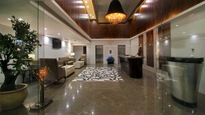 A modern lobby with a reception desk, seating area, and a large potted plant.