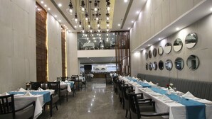 A restaurant with long tables, chairs, and a high ceiling with hanging lights.