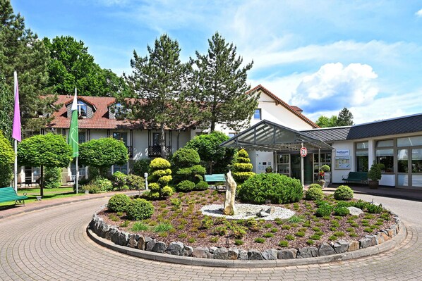 A hotel with a garden, a fountain, and a covered entrance. - Landhotel Schnuck (Schneverdingen)