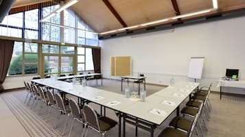 A conference room with a long table, chairs, a whiteboard, and a projector.