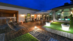Un área de estar moderna con asientos exteriores, una piscina y un patio bien iluminado.