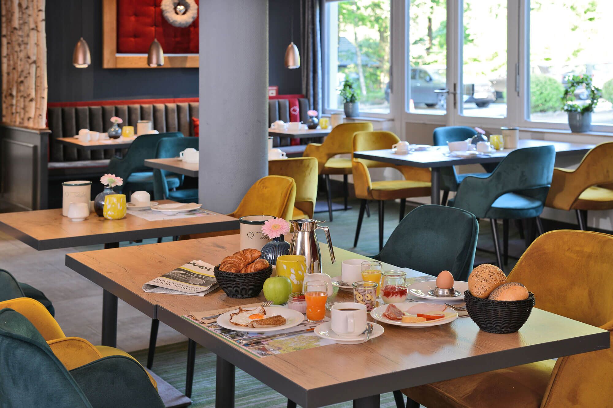 Une table mise pour le petit-déjeuner, avec des tables, des chaises et une vue sur l’extérieur.