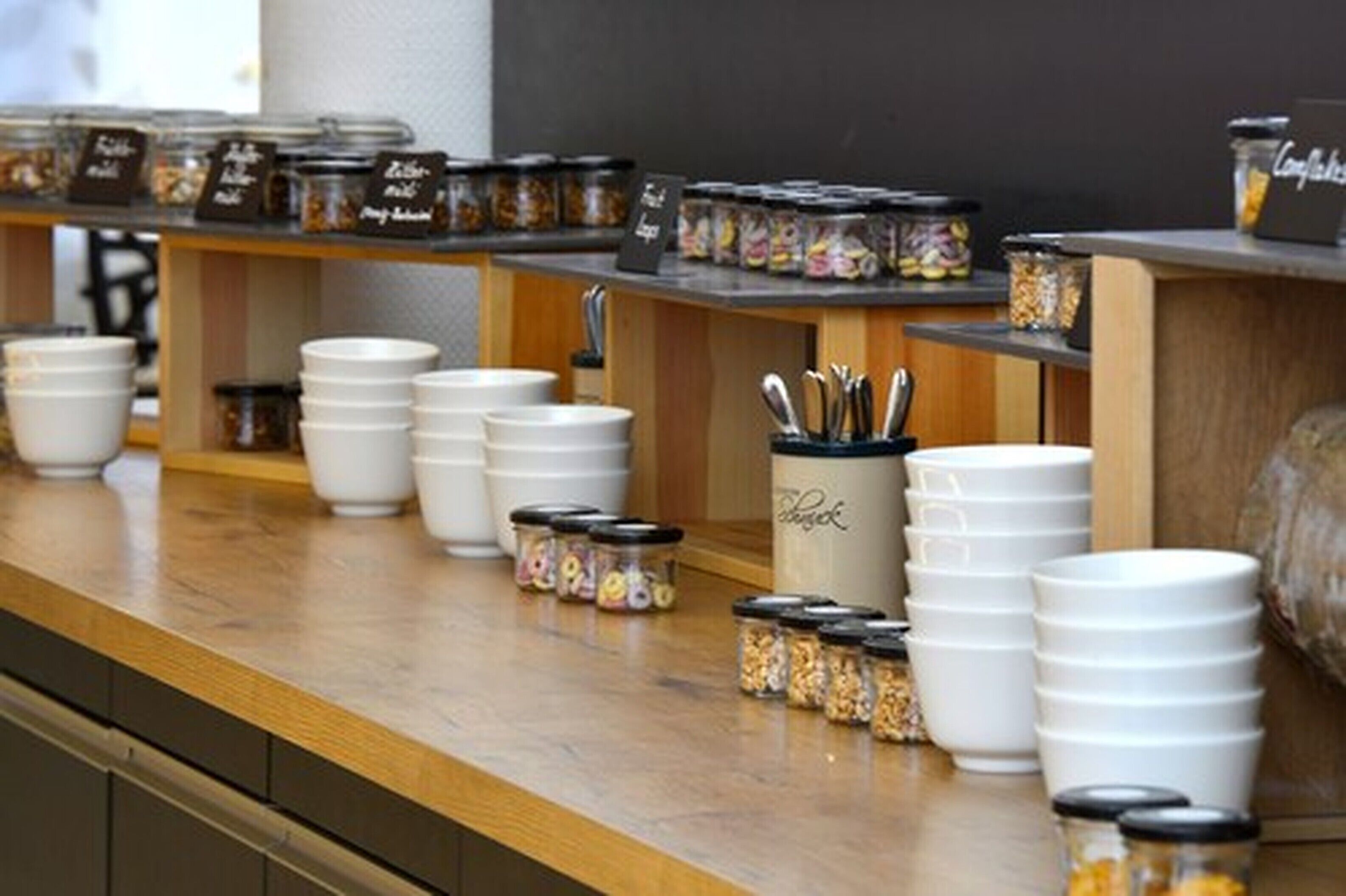 A buffet setup with white bowls and jars of condiments.