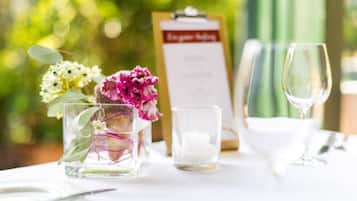 A table set for dining with a menu, a glass candle, and a glass vase with flowers.