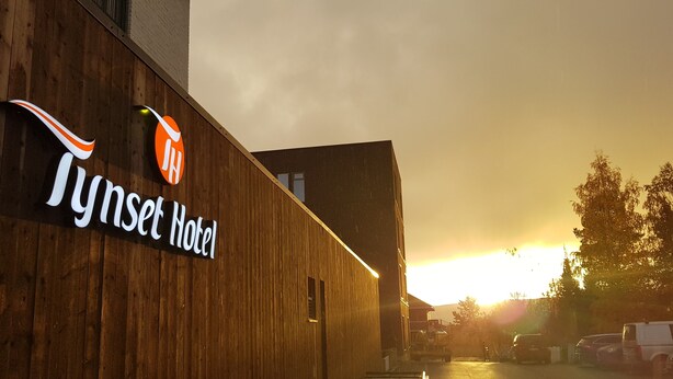 Un edificio de madera con un letrero que dice "Tynset Hotel" y un logotipo encima.