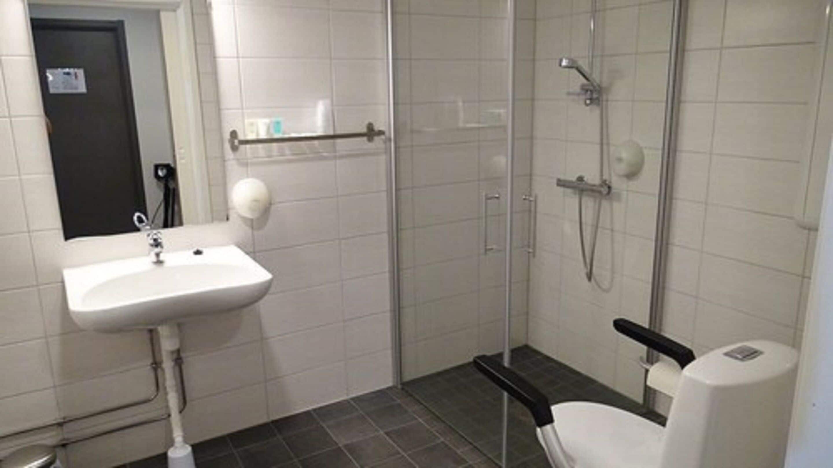 A bathroom with a white sink, a glass shower enclosure, and a toilet.