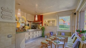 A modern kitchen with a bar area, seating with cushioned stools, and a view of the outside. - Hotel Europa (Sorico)