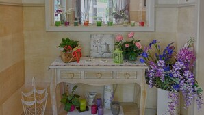 A room with a wooden console table, a mirror above it, and a vase with flowers. - Hotel Europa (Sorico)