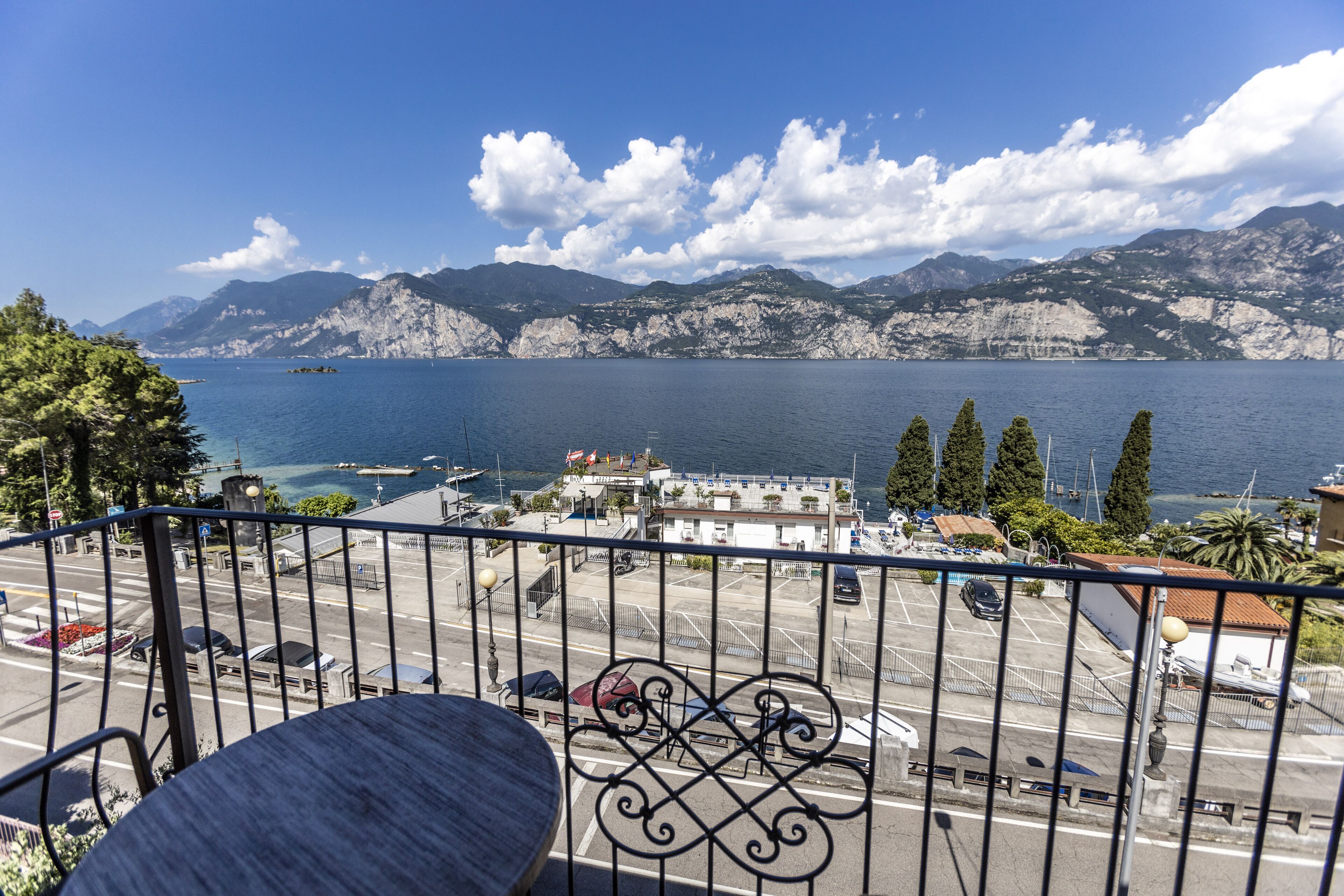 Un balcon avec vue sur une ville côtière, un parking et des montagnes en arrière-plan.