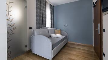 A modern room with a grey sofa, a wooden floor, and a blue wall.