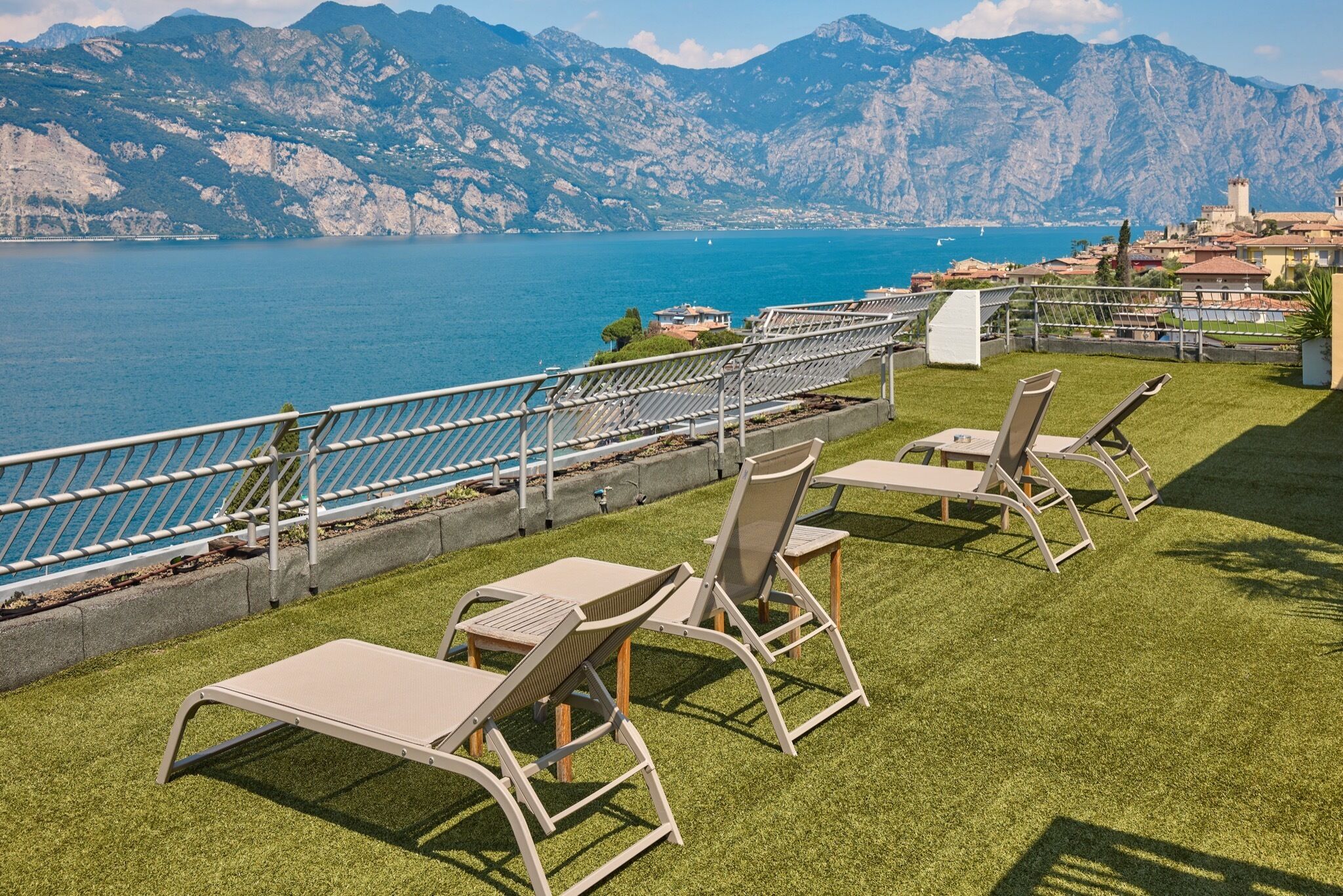 A terrace with outdoor seating and a view of a lake and mountains.