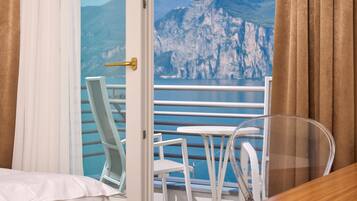 Ein Hotelzimmer mit Balkon, weißen Möbeln und Blick auf Berge und Wasser.