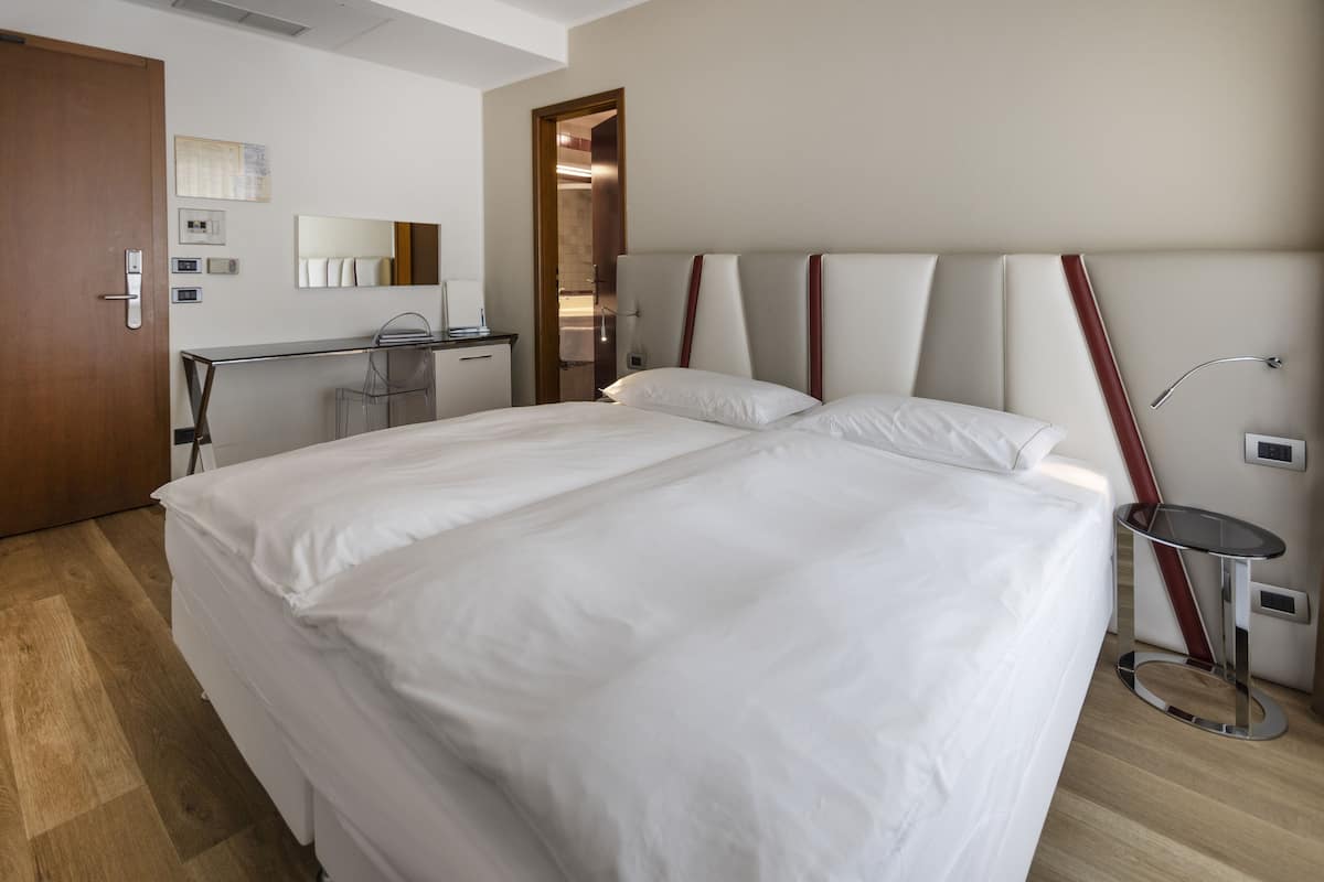 Una habitación de hotel moderna con una cama grande, un escritorio y un espejo.