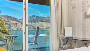 A hotel room with a glass door leading to a balcony with a mountain view. - Hotel Capri (Malcesine)