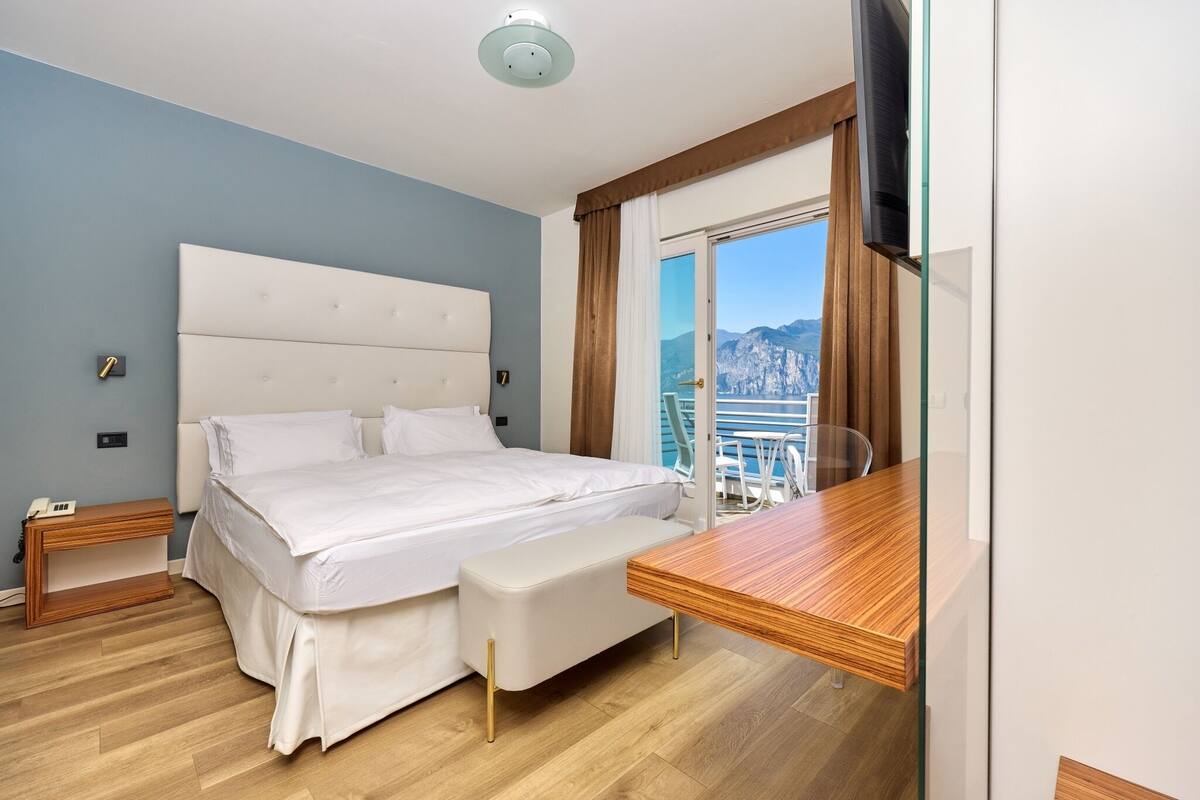 Un dormitorio con cama, mesita de noche y escritorio con silla.