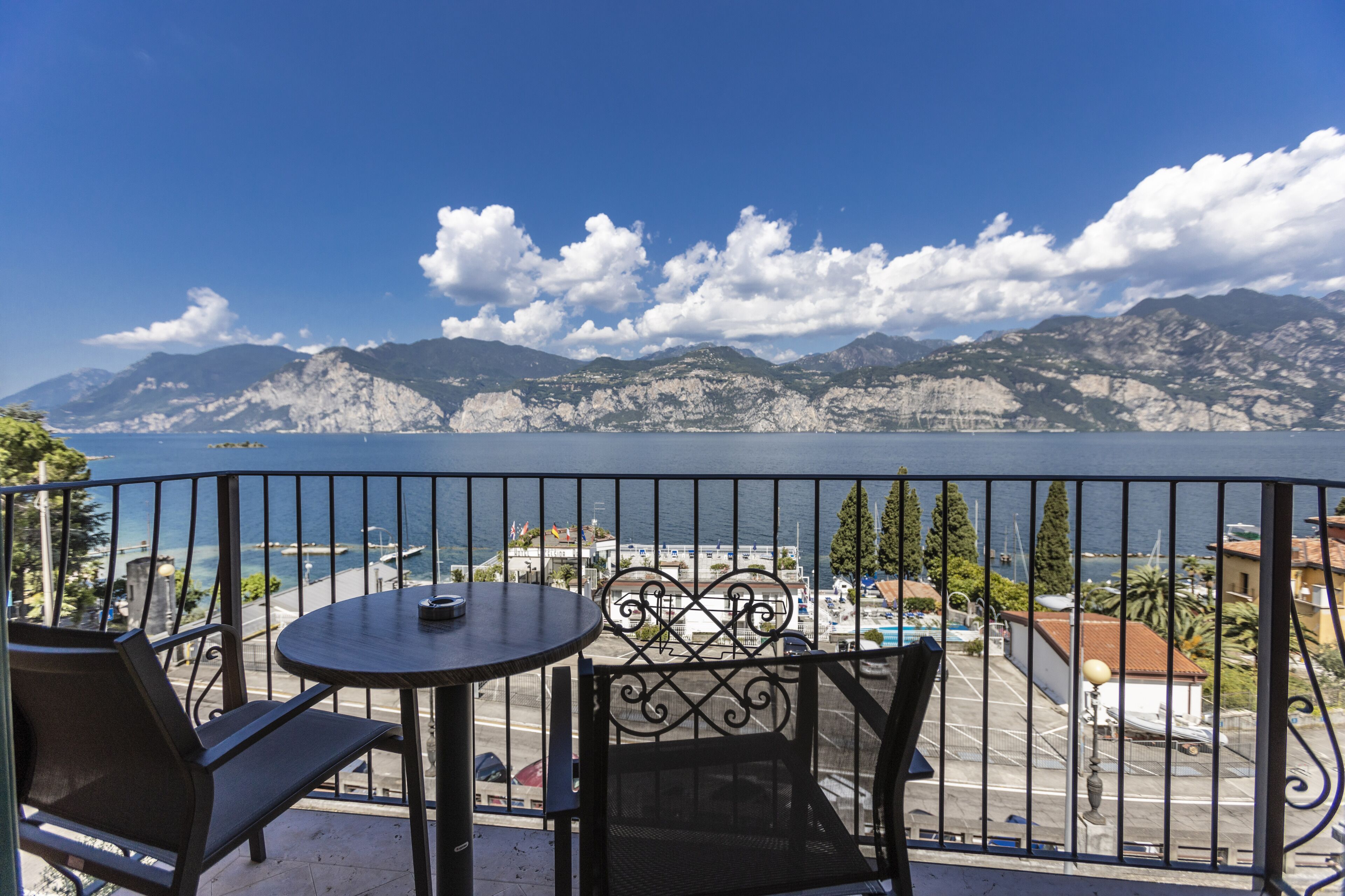 Un balcón con mesa y sillas con vista a un lago y montañas.