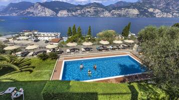 Relax by the pool surrounded by lounge chairs and umbrellas, with a view of the mountainous coastline.