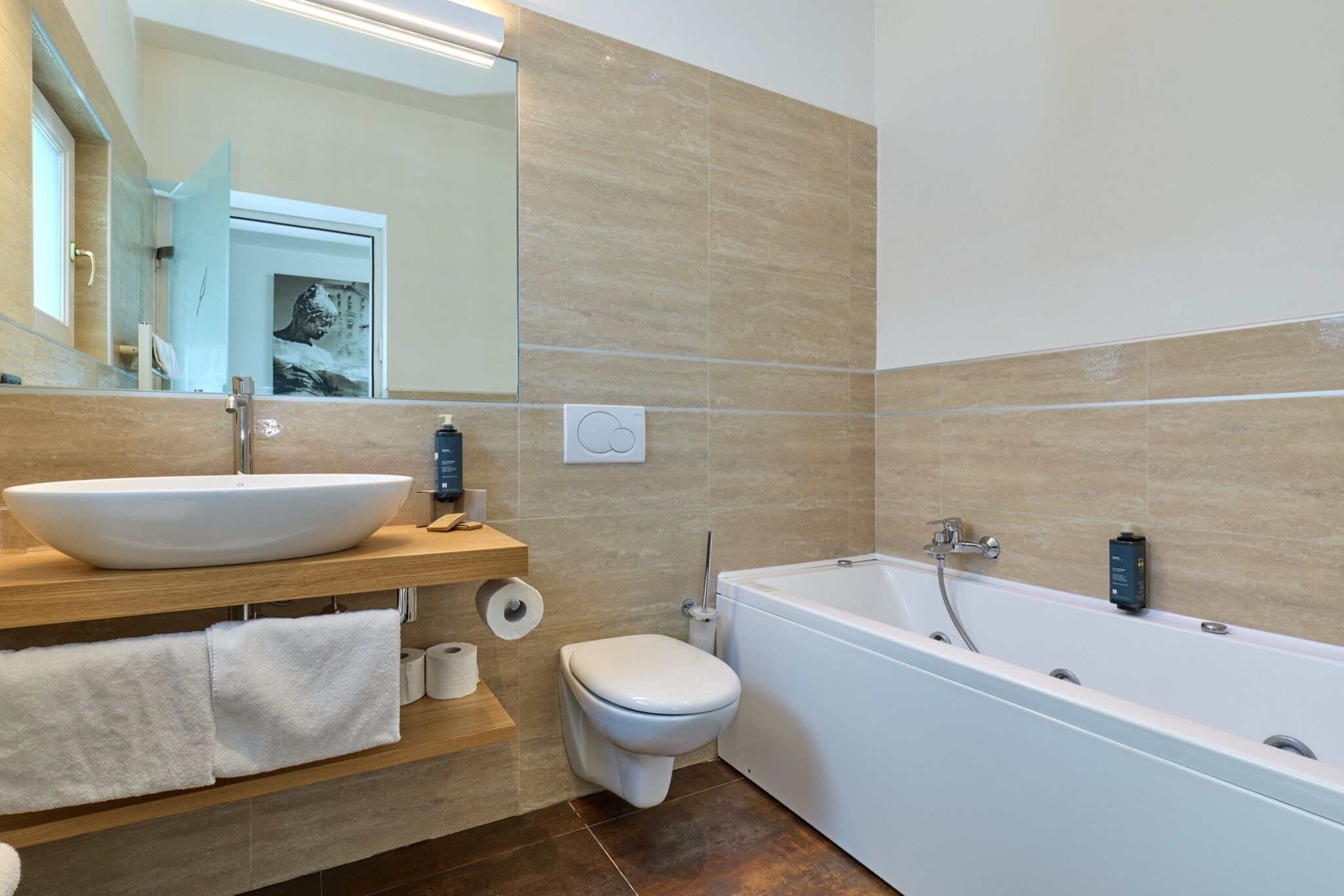 Un baño moderno con una bañera blanca grande, un lavamanos tipo pedestal y un inodoro.