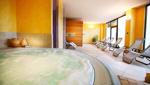 A spa area with a hot tub, lounge chairs, and a wooden wall. - Hotel Capri (Malcesine)
