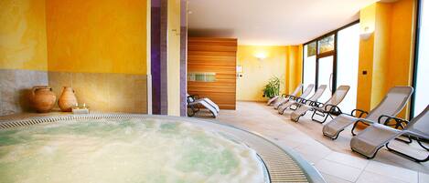A spa area with a hot tub, lounge chairs, and a wooden wall.