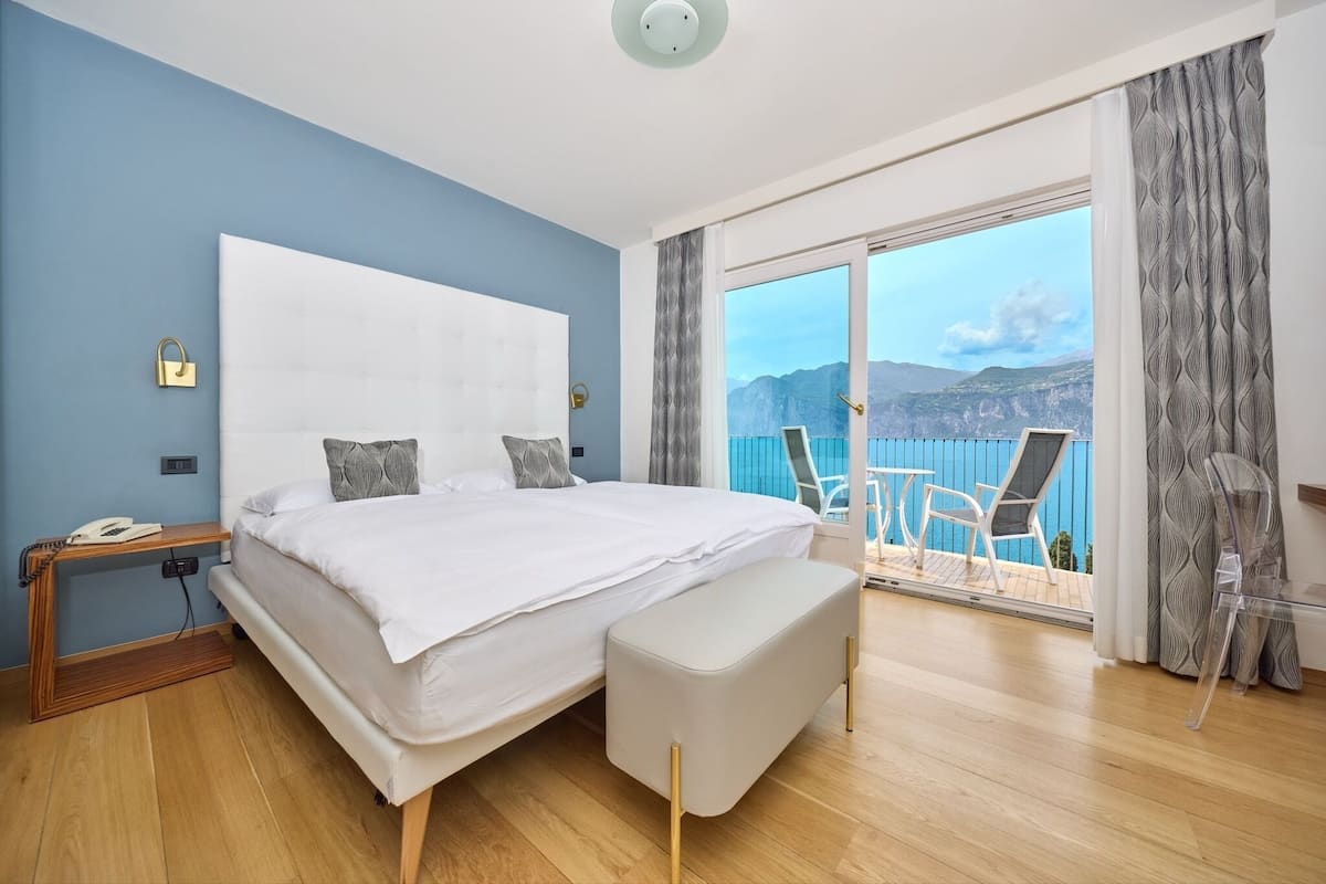 Un dormitorio con una cama grande, una mesita de noche con un teléfono y vistas al exterior.