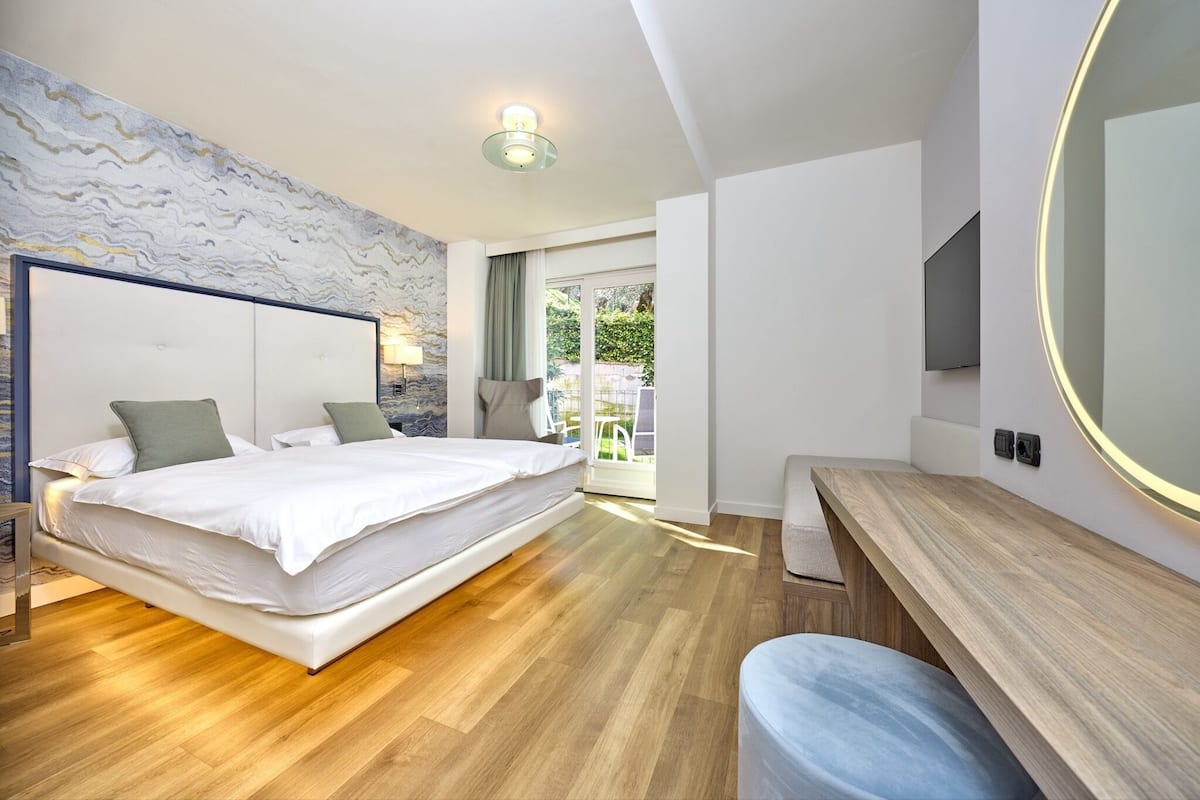 Un dormitorio moderno con una cama grande, un escritorio de madera y un espejo amplio.