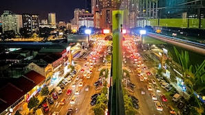 A nighttime cityscape with a busy intersection and tall buildings, including a prominent skyscraper with illuminated signage. - InnB Park Hotel (Kuala Lumpur)