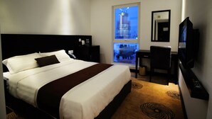 A hotel room with a large bed, a desk with a chair, a television, and a window with a view of a building. - InnB Park Hotel (Kuala Lumpur)