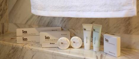 A bathroom counter with toiletries and a towel branded with "INN B PARK HOTEL".