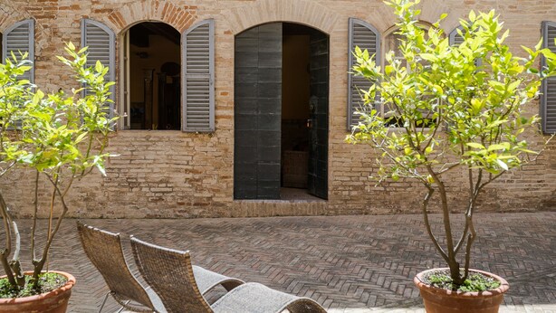 A brick building with arched windows and a paved courtyard. - Palazzo Romani Adami (Fermo)