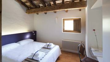 Quarto com cama, janela, radiador e uma cadeira.