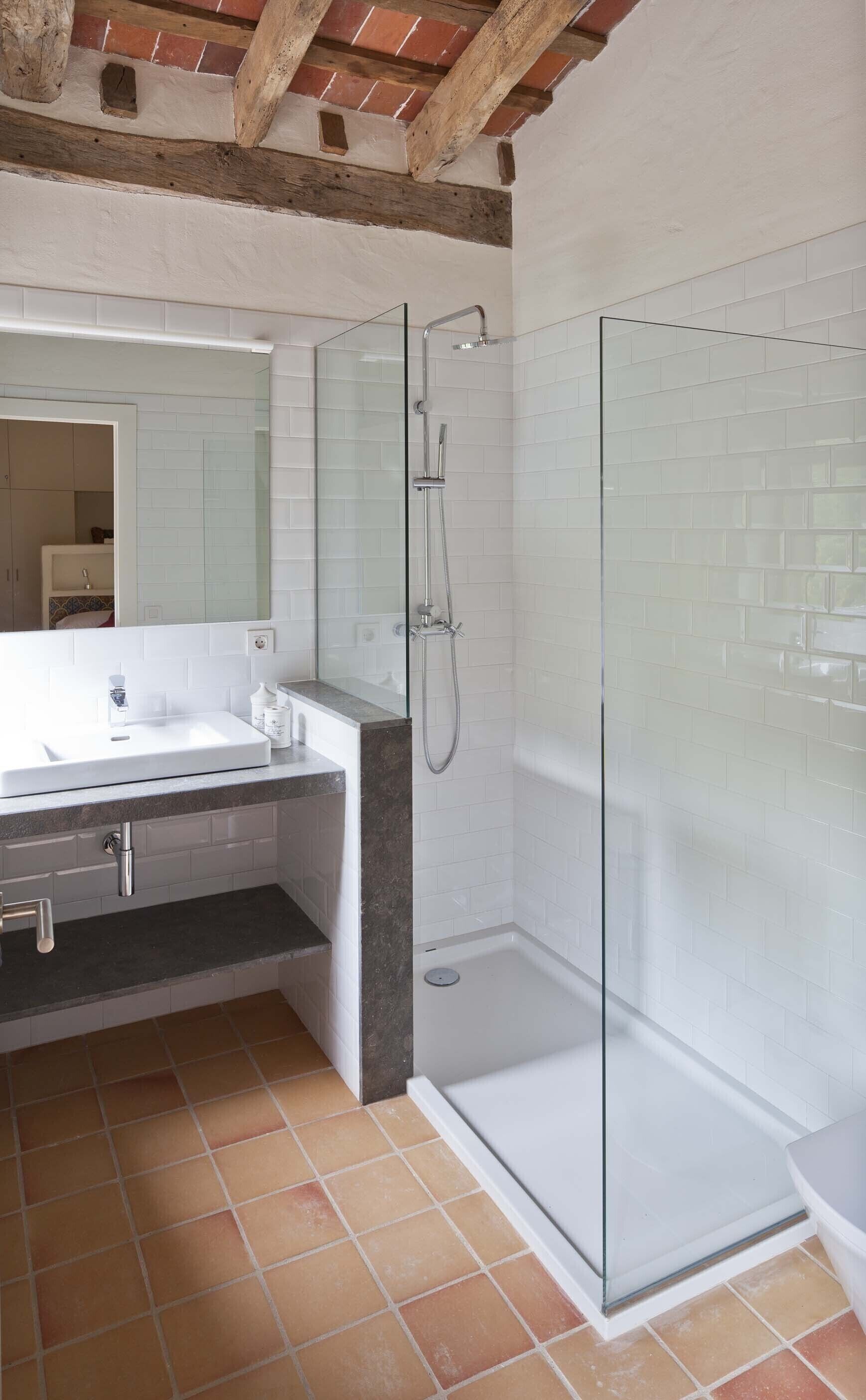 Een moderne badkamer met een douchecabine van glas, een wit wastafelmeubel en een betegelde vloer.