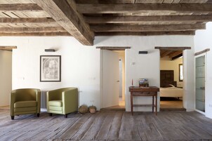Una habitación con vigas de madera, una cama, un escritorio y dos sillones.