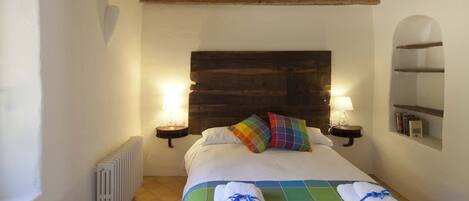 A neatly made bed with a colorful quilt, two bedside lamps, and a wooden headboard.