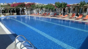 Una piscina al aire libre, sombrillas, sillones reclinables de piscina