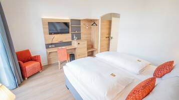 A modern hotel room with a large bed, a desk, a TV, and a shower area.