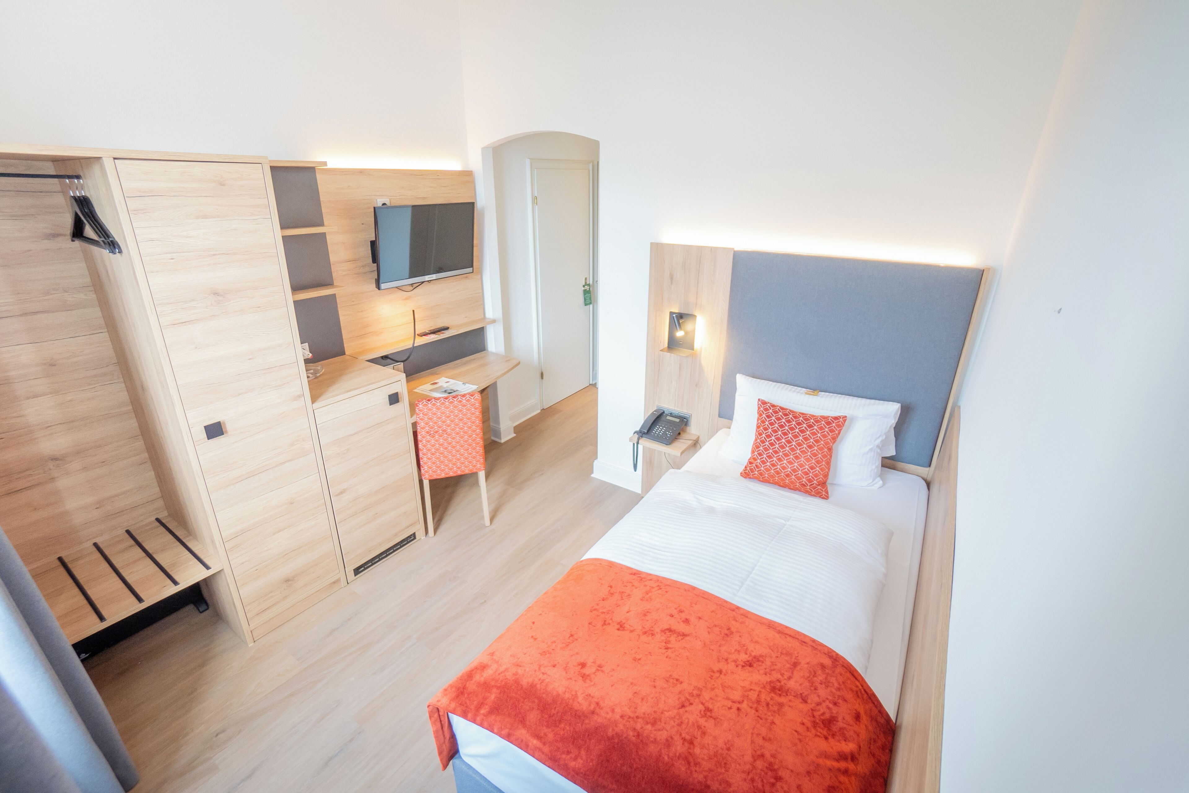 Ein Hotelzimmer mit Bett, Schreibtisch, Fernseher und Kleiderschrank.