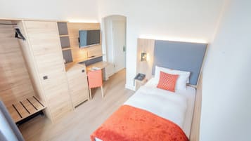 Ein Hotelzimmer mit Bett, Schreibtisch, Fernseher und Kleiderschrank.