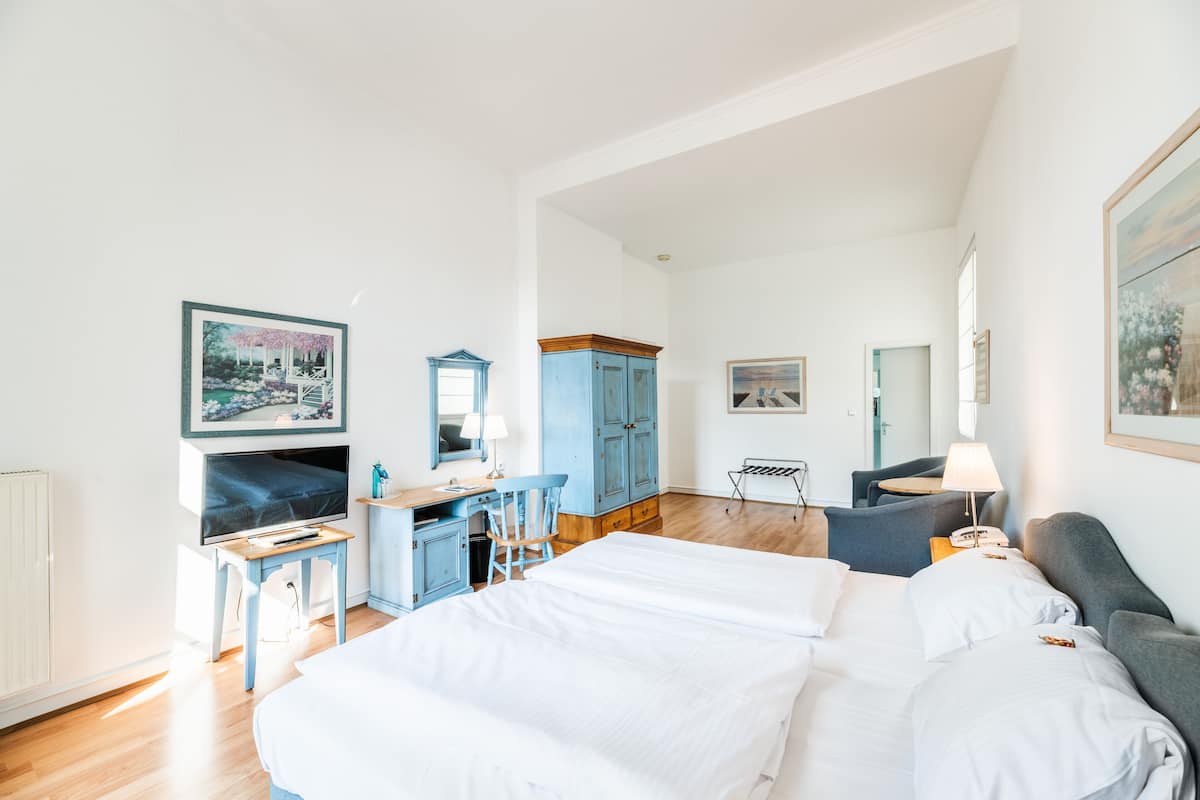 A hotel room with a bed, a desk, a chair, a TV, and a wardrobe.