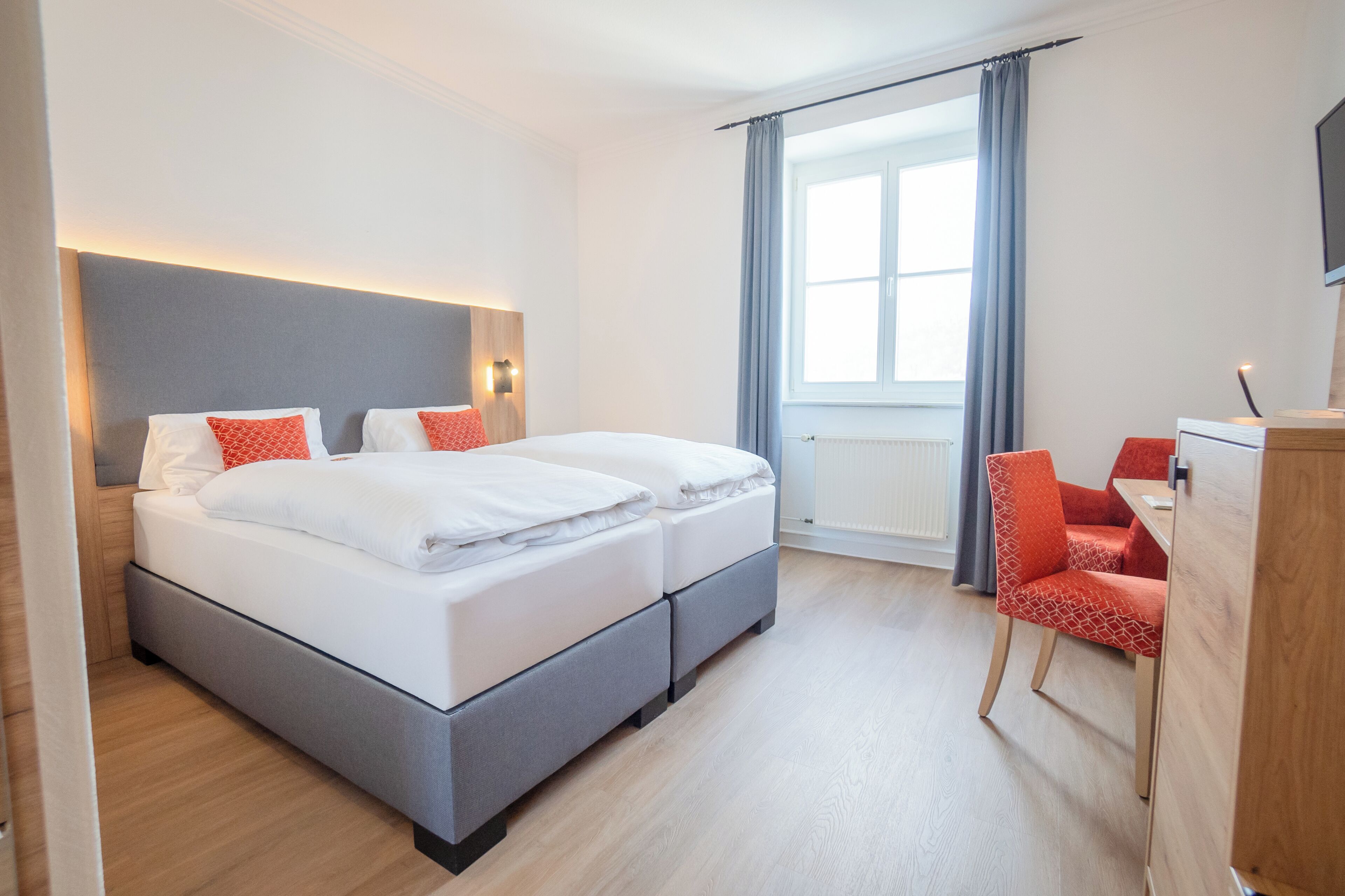 A modern hotel room with a large bed, a desk, and a chair.