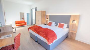 A modern hotel room with a large bed, a desk, and a chair.